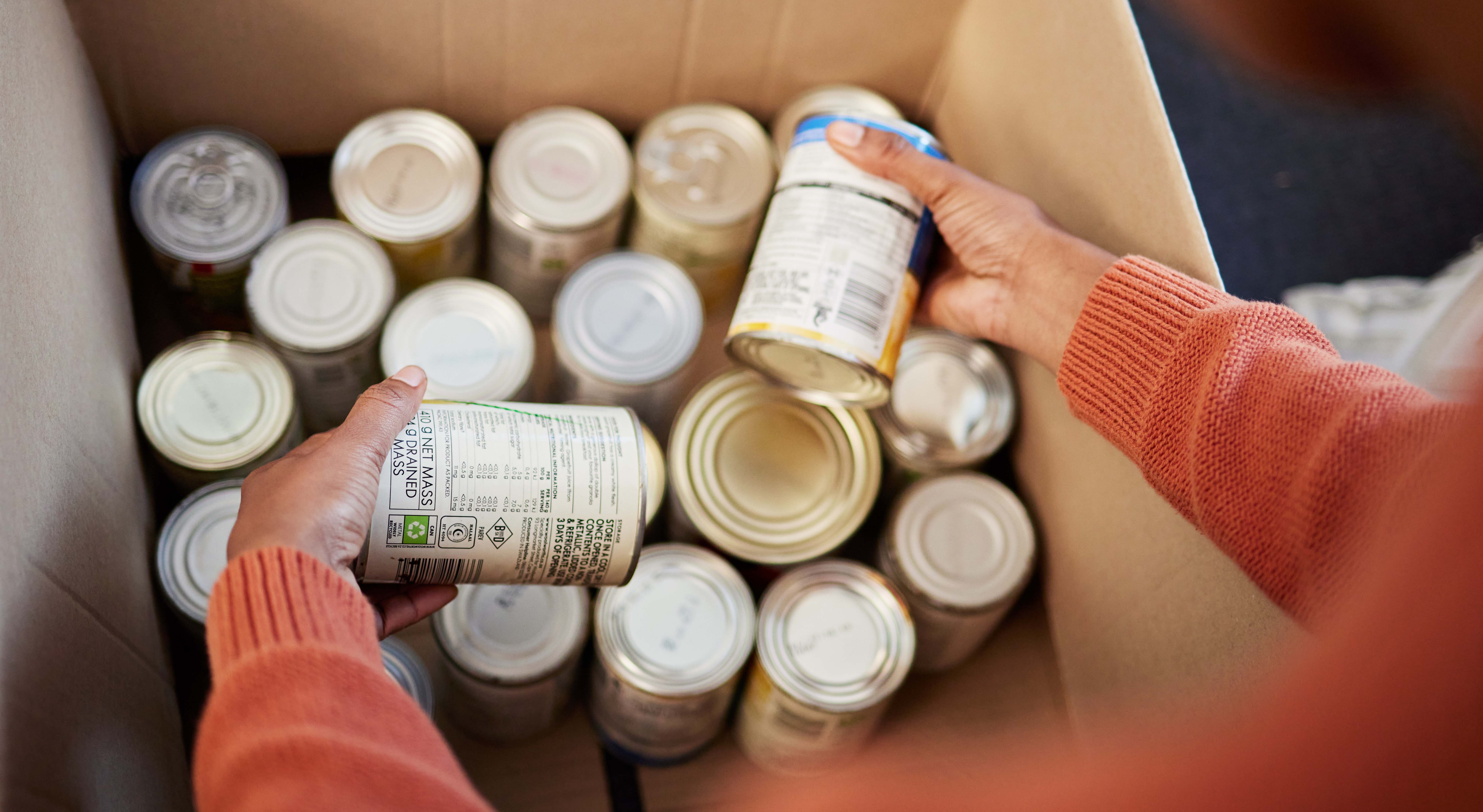 Hands placing food cans into box